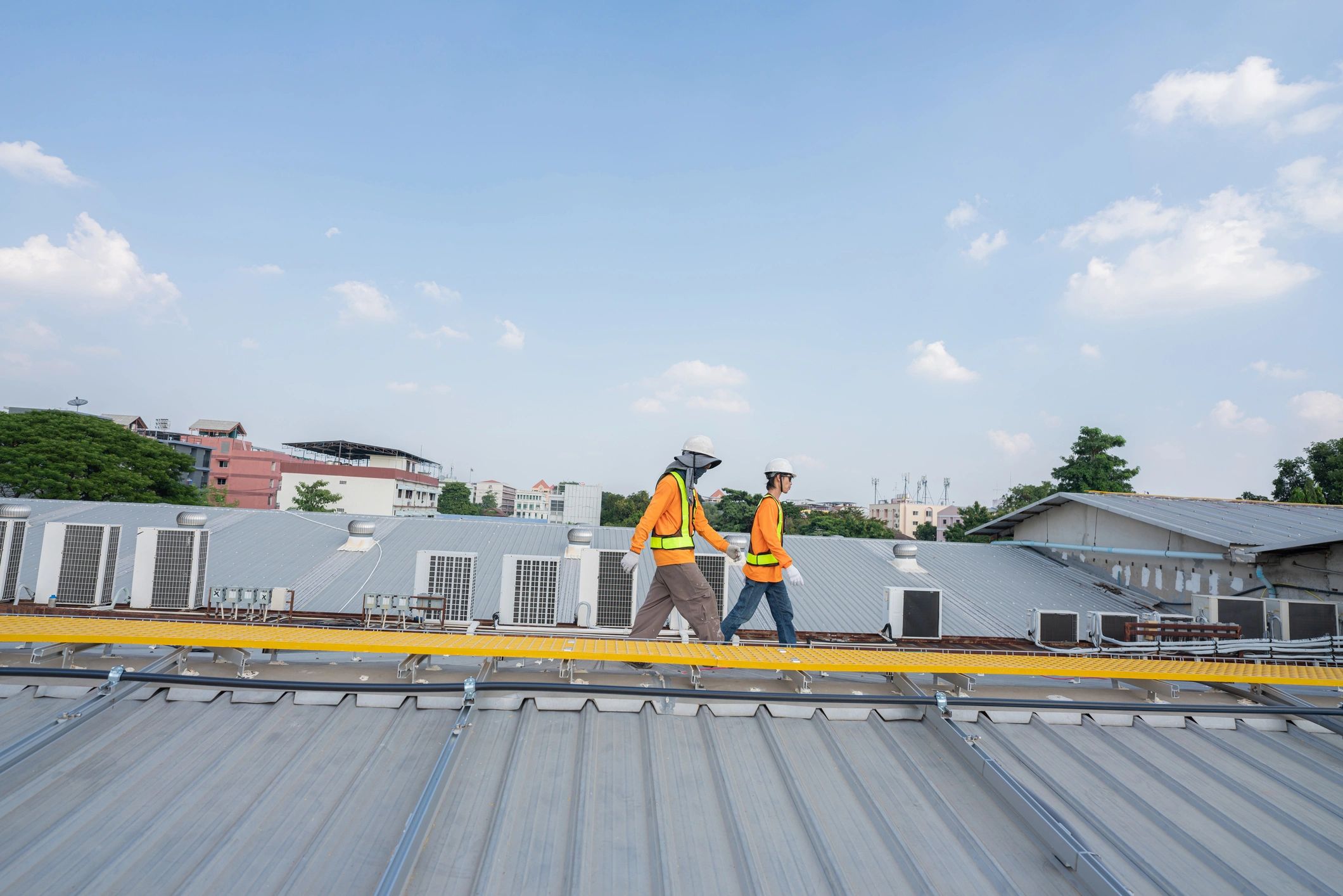 Men technicians carrying photovoltaic solar modules on roof